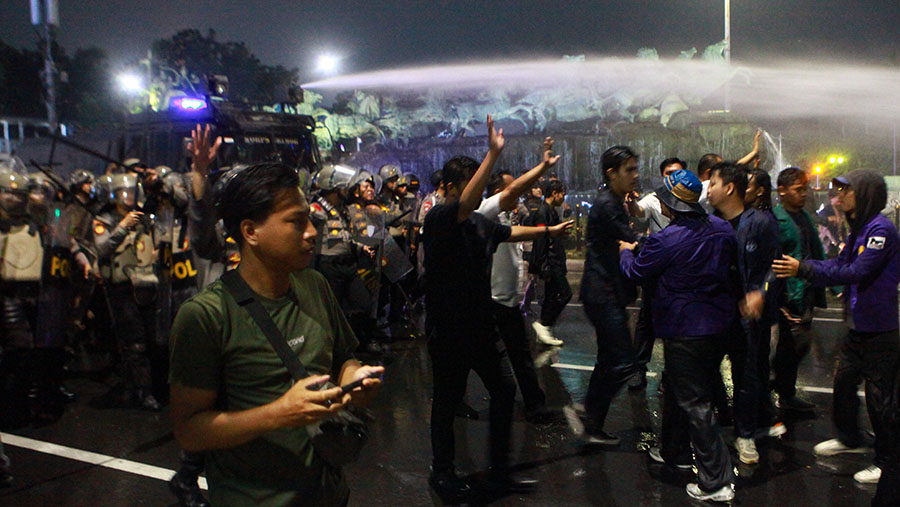 Barrier pembatas lalu dibongkar polisi dan aparat keaman maju untuk membubarkan massa. (Bloomberg Technoz/Andrean Kristianto)