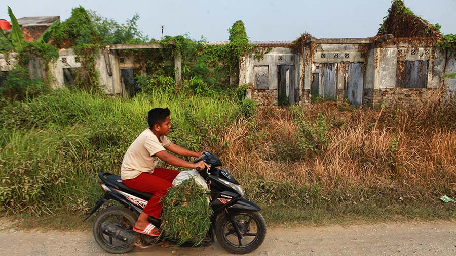 Warga melintas di depan rumah yang terbengkalai di Perumahan Karawang Baru, Jawab Barat, Rabu (24/7/2024). (Bloomberg Technoz/Andrean Kristianto)