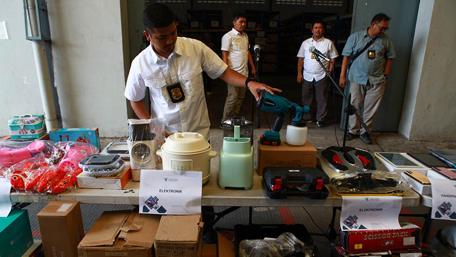 Petugas merapihkan barang impor ilegal saat rilis di pergudangan Kamal Muara, Jakarta, Jumat (25/7/2024). (Bloomberg Technoz/Andrean Kristianto)