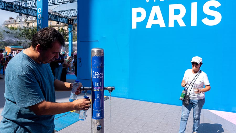 Penonton mengisi ulang botol air di fanzone Hotel de Ville Olimpiade Paris 2024 di Paris, Prancis, Selasa (30/7/2024). (Nathan Laine/Bloomberg)