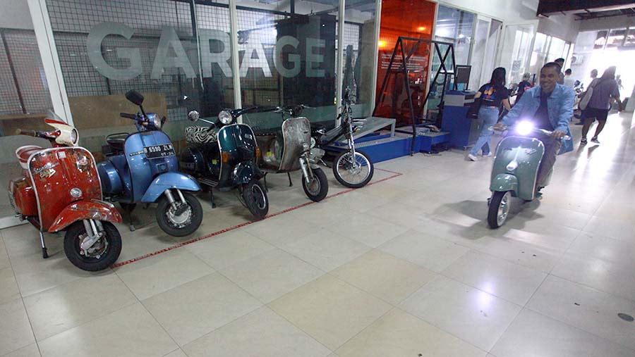 Pengunjung mencoba Vespa yang dikonversi menjadi motor listrik di Elders Garage, Jakarta, Jumat (2/8/2024).  (Bloomberg Technoz/Andrean Kristianto)
