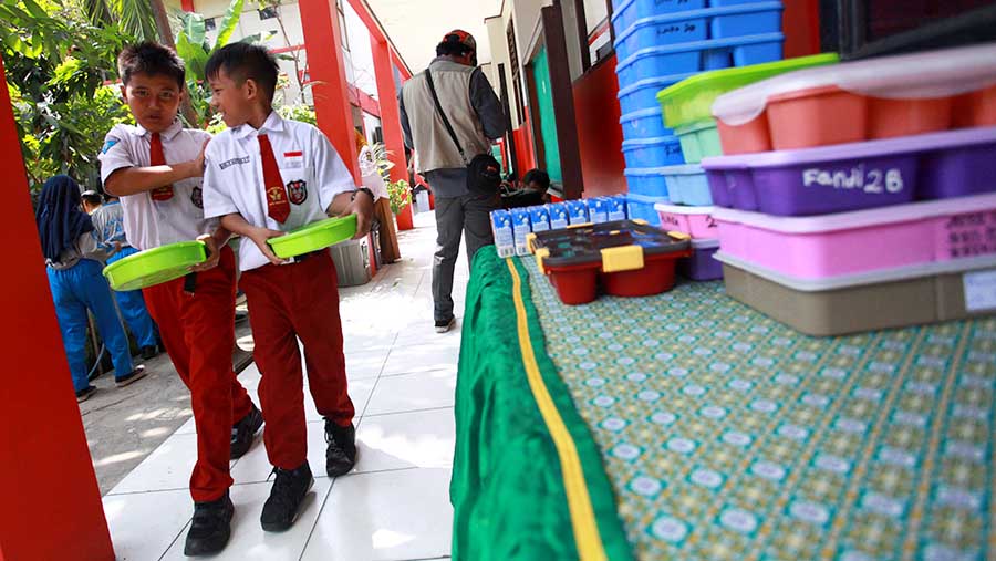 Siswa membawa kotak makan saat uji coba program makan siang gratis di SDN 4 Tangerang, Senin (5/8/2024). (Bloomberg Technoz/Andrean Kristianto)
