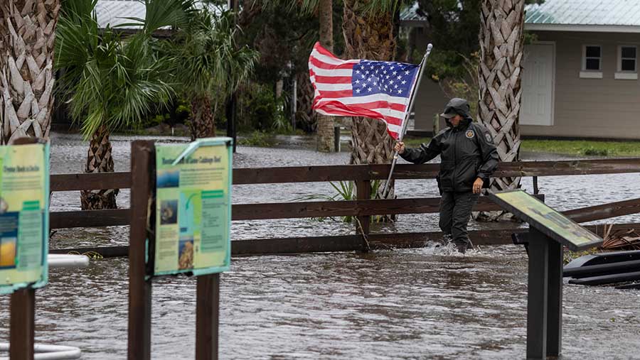 Petugas menyingkirkan bendera AS dari banjir setelah Badai Debby menerjang Suwannee, Florida, AS, Senin (5/8/2024). (Christian Monterrosa/Bloomberg)