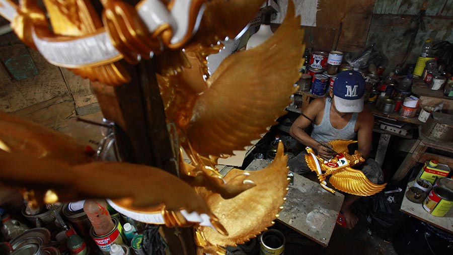 Pekerja mengecat patung Garuda Pancasila di Garuda Fiber, Halim, Jakarta Timur, Jumat (9/8/2024). (Bloomberg Technoz/Andrean Kristianto)