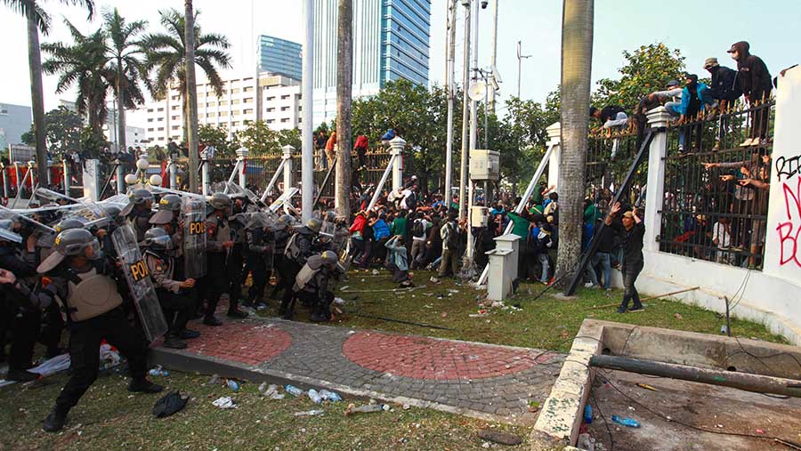 Massa aksi melemparkan botol dan batu ke arah aparat keamanan yang berjaga. (Bloomberg Technoz/Andrean Kristianto)