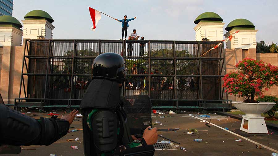 Beberapa peserta aksi menaiki pagar kompleks gedung parlemen tersebut. (Bloomberg Technoz/Andrean Kristianto)