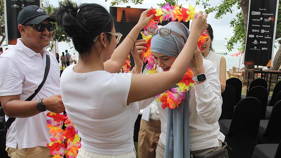 Sebelum melakukan pelepasan tukik ke pantai, peserta menerima pengalungan bunga. (Bloomberg Technoz/Andrean Kristianto)