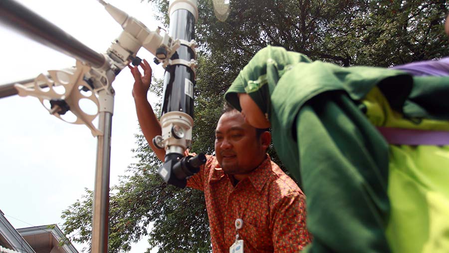 Siswa SD melihat bentuk matahari melalui teropong optik di MI Dakwah Islamiyah, Jakarta, Kamis (12/11/2024). (Bloomberg Technoz/Andrean Kristianto)