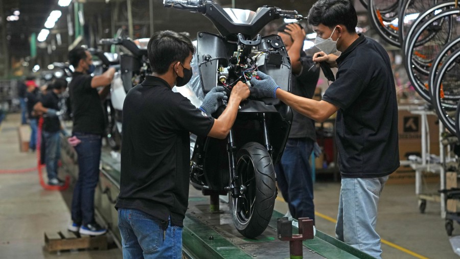 Workers labor on an E-Motor electric motorcycle on the assembly line of PT Terang Dunia Internusa's United Bike factory in Citeureup./Bloomberg-Dimas 