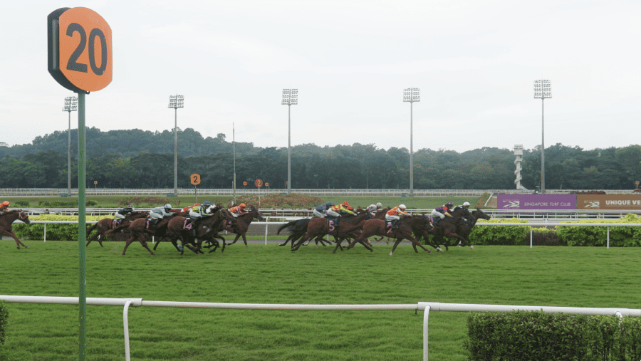 Para joki berlomba pada hari terakhir perlombaan Singapore Turf Club.(Fotografer Low De Wei/Bloomberg)