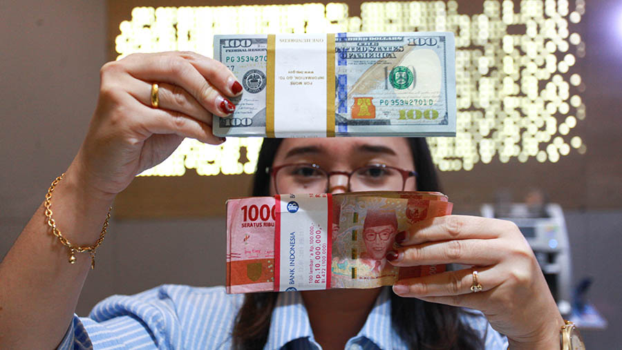 Karyawan menunjukkan uang rupiah dan dolar AS di Jakarta, Jumat (11/10/2024). (Bloomberg Technoz/Andrean Kristianto)