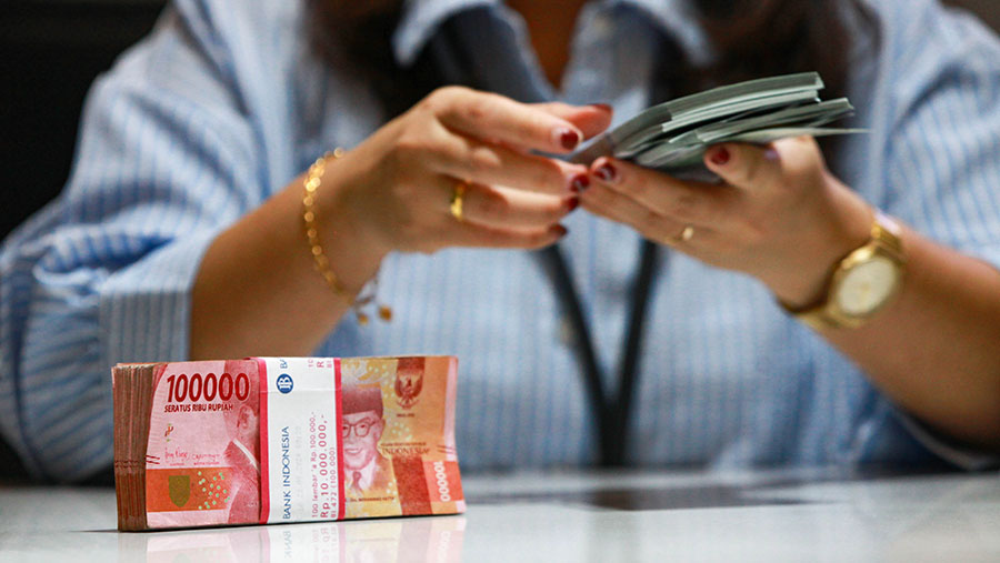 Karyawan menghitung uang dolar AS dan rupiah di Jakarta, Jumat (11/10/2024). (Bloomberg Technoz/Andrean Kristianto)