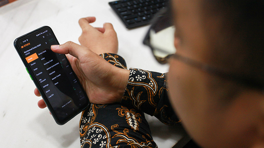 Karyawan membuka aplikasi transaksi saham mobile M-STOCK milik Mirae Asset di Jakarta, Kamis (8/8/2024). (Bloomberg Technoz/Andrean Kristianto)
