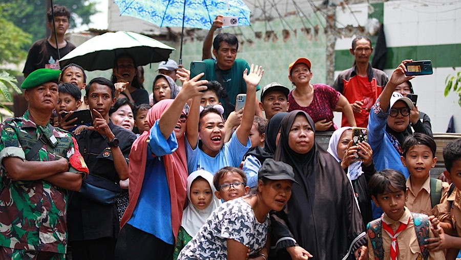 Di luar sekolah sejumlah warga dan anak sekolah telah menunggu Wapres Gibran. (Bloomberg Technoz/Andrean Kristianto)