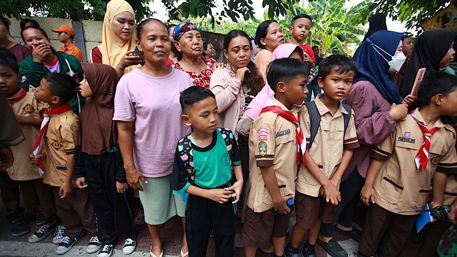 Warga dan anak sekolah menunggu di depan sekolah hingga Gibran meninggalkan lokasi kunjungannya. (Bloomberg Technoz/Andrean Kristianto)