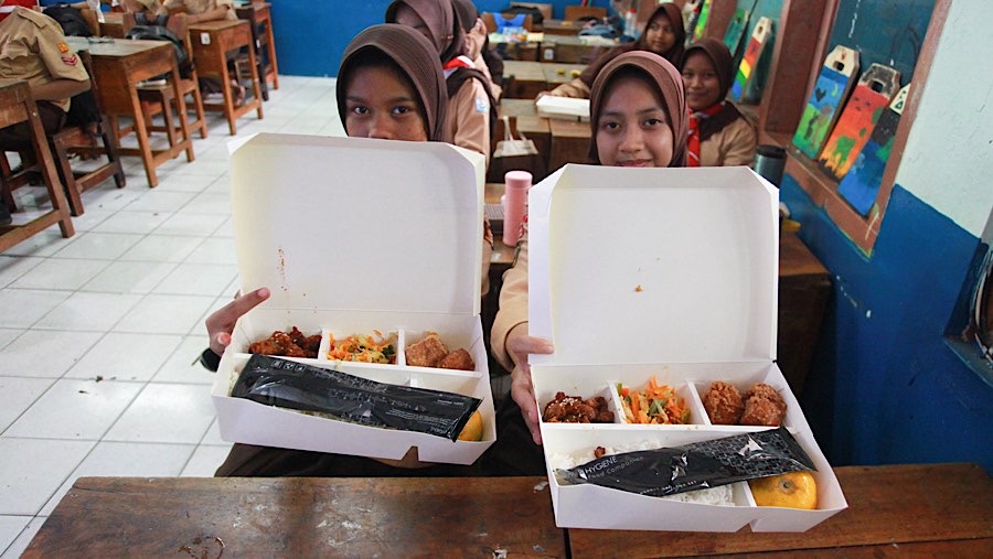 Siswi memperlihatkan menu makan siang bergizi gratis di SMPN 270, Jakarta, Rabu (23/10/2024). (Bloomberg Technoz/Andrean Kristianto)