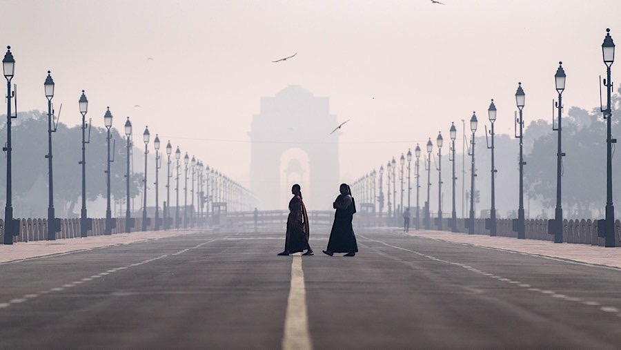 Pejalan kaki melewati Gerbang India yang diselimuti kabut asap polusi di New Delhi, India, Selasa (29/10/2024). (Anindito Mukherjee/Bloomberg)