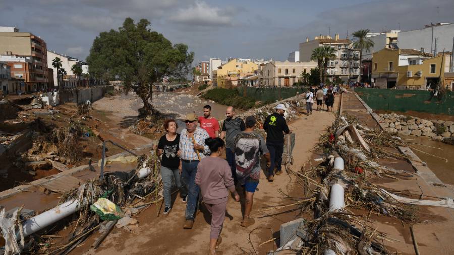 Warga menyeberangi jembatan melalui tumpukan puing setelah banjir di Paiporta, Valencia, Spanyol. (David Ramos/Getty Images Europe via Bloomberg)