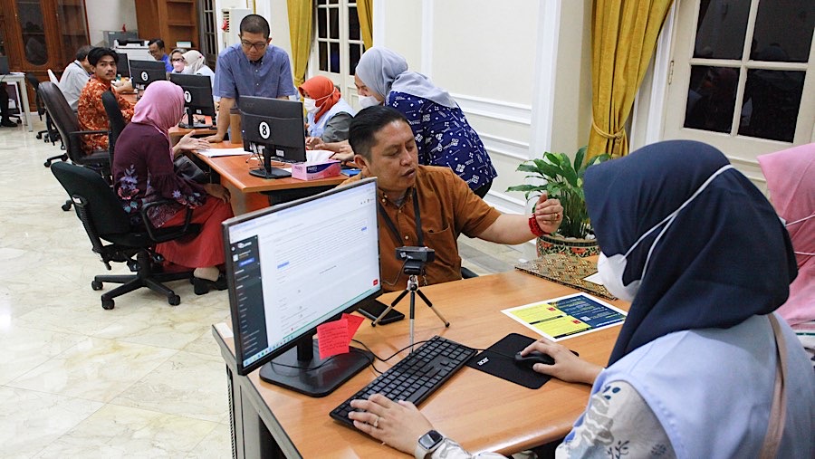 Masyarakat yang mengadu dilayani oleh petugas yang sudah menanti di meja dengan mengenakan rompi biru muda. (Bloomberg Technoz/Andrean Kristianto)