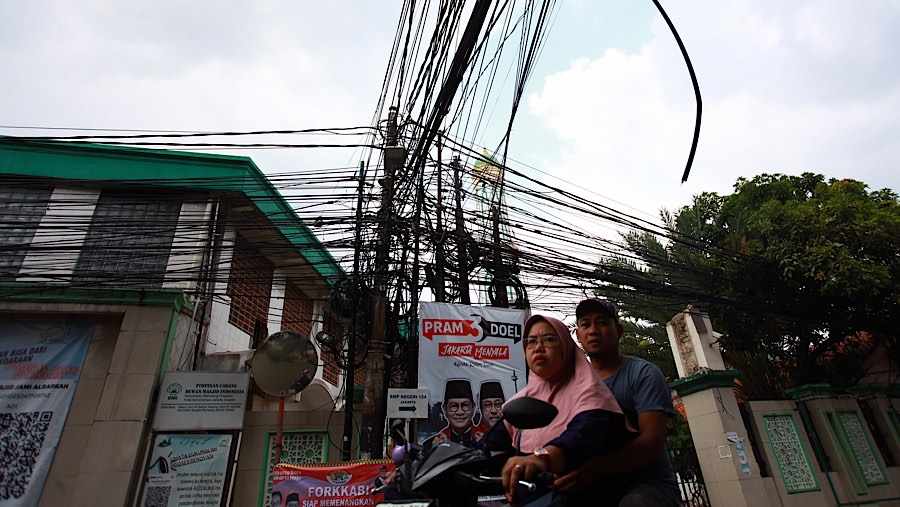 Pengendara melintas di bawah kabel yang semrawut di kawasan Kemang, Jakarta, Rabu (13/11/2024). (Bloomberg Technoz/Andrean Kristianto)