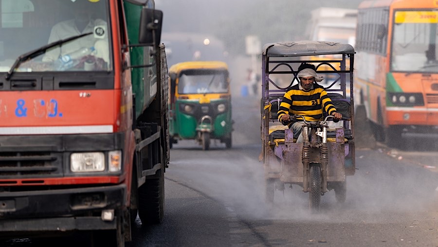 Kendaraan menyemprotkan air ke jalan untuk meredam debu selama polusi udara di New Delhi, India, Kamis (14/11/2024). (Anindito Mukherjee/Bloomberg)