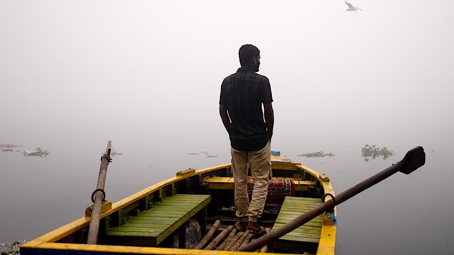 Seorang berdiri di atas perahu di Sungai Yamuna yang diselimuti kabut asap di New Delhi, India, Kamis (14/11/2024). (Anindito Mukherjee/Bloomberg)