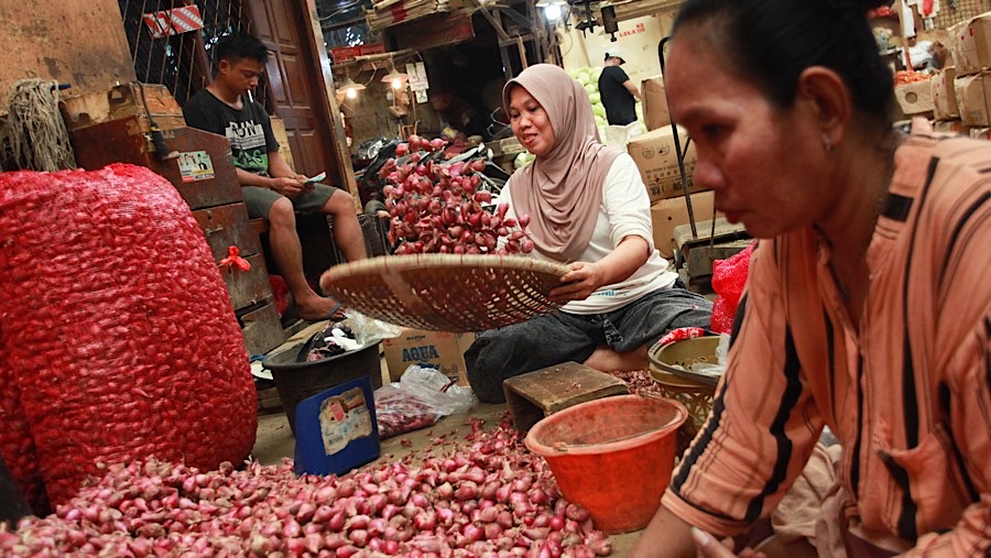 Pekerja membersihkan bawang merah di Pasar Induk, Kramat Jati, Senin (2/12/2024), (Bloomberg Technoz/Andrean Kristianto)