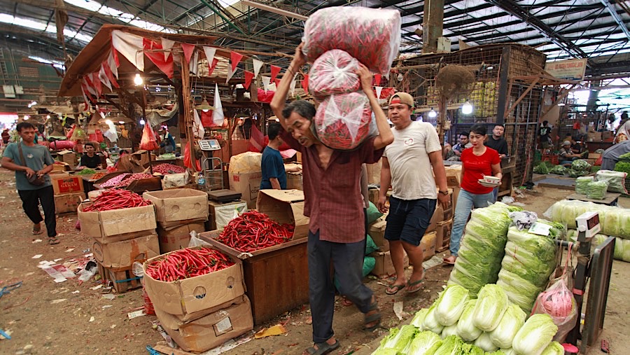 Seseorang mengangkut barang di Pasar Induk, Kramat Jati, Senin (2/12/2024). (Bloomberg Technoz/Andrean Kristianto)