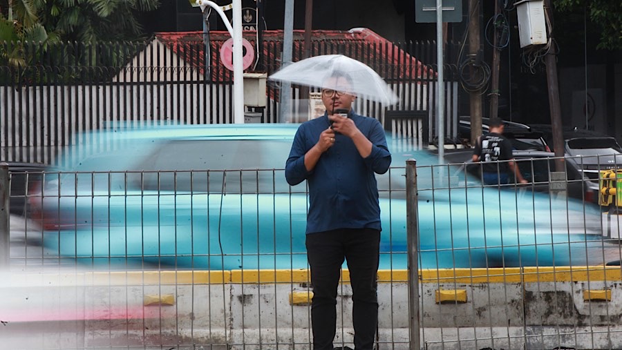 Warga bersiap menyeberang saat angin kencang di kawasan Sudirman, Jakarta, Selasa (3/12/2024). (Bloomberg Technoz/Andrean Kristianto)