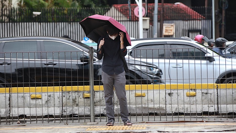 Warga bersiap menyeberang saat angin kencang di kawasan Sudirman, Jakarta, Selasa (3/12/2024). (Bloomberg Technoz/Andrean Kristianto)
