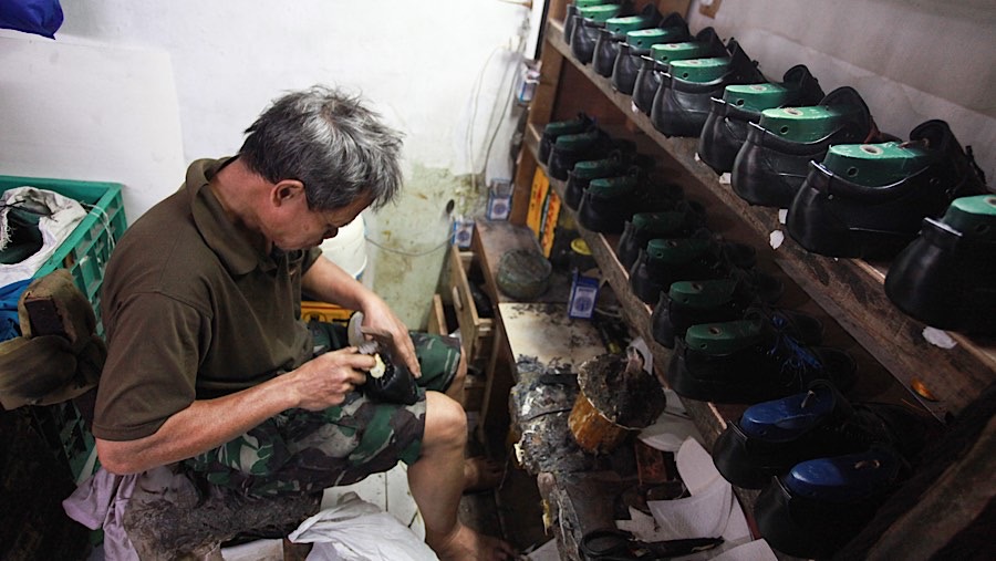 Pekerja menyelesaikan pembuatan sepatu di industri rumahan di Cakung, Jakarta Timur, Selasa (3/12/2024). (Bloomberg Technoz/Andrean Kristianto)