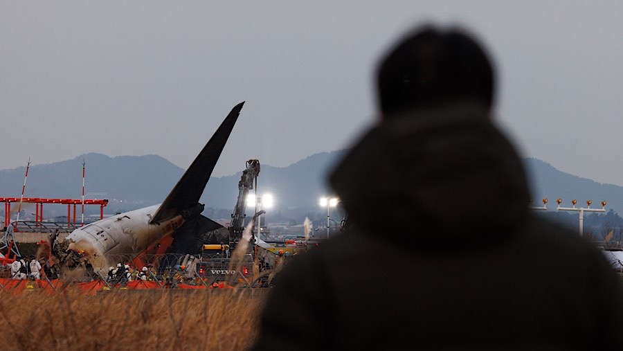 Ekor pesawat Jeju Air yang mengalami kecelakaan di Bandara Internasional Muan, Korea Selatan, Minggu (29/12/2024). (SeongJoon Cho/Bloomberg)