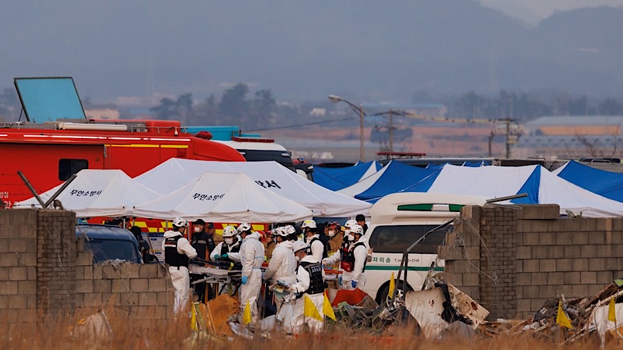 Petugas penyelamat di lokasi kebakaran pesawat Jeju Air di Bandara Internasional Muan, Korea Selatan, Minggu (29/12/2024). (SeongJoon Cho/Bloomberg)