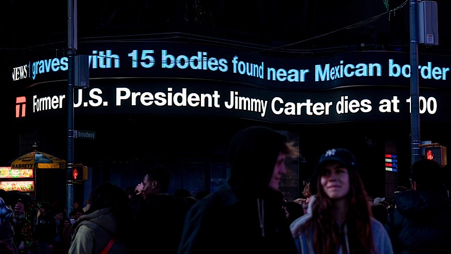 Ticker berita informasi tentang meninggalnya mantan Presiden AS Jimmy Carter di Times Square, New York, AS, Minggu (29/12/2024). (Al Drago/Bloomberg)