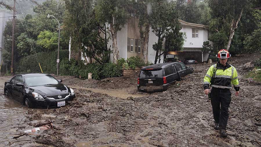 Petugas berjalan di atas lumpur akibat tanah longsor usai badai melanda Los Angeles, AS, Senin (5/2/2024). (Eric Thayer/Bloomberg)