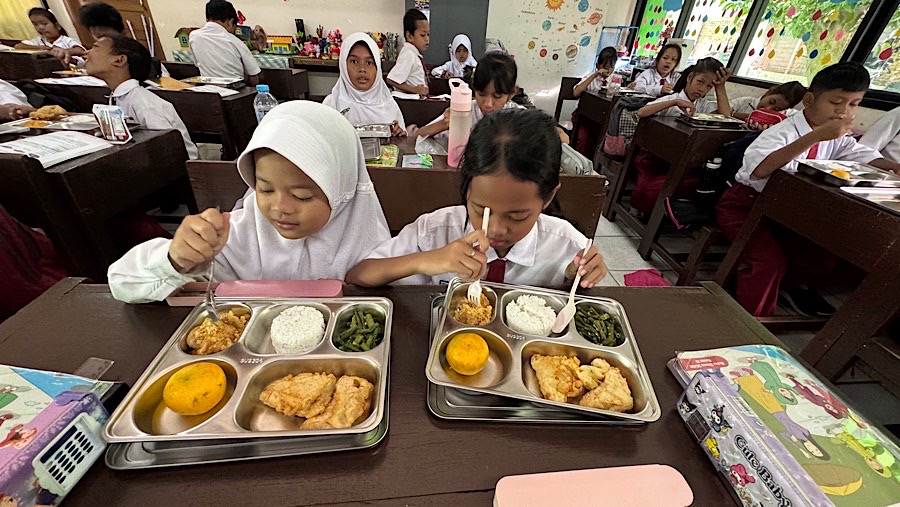 Sejumlah murid menyantap makanan bergizi gratis (MBG) di SDN 15 Slipi, Jakarta, Senin (6/1/2025). (Bloomberg Technoz/Andrean Kristianto)