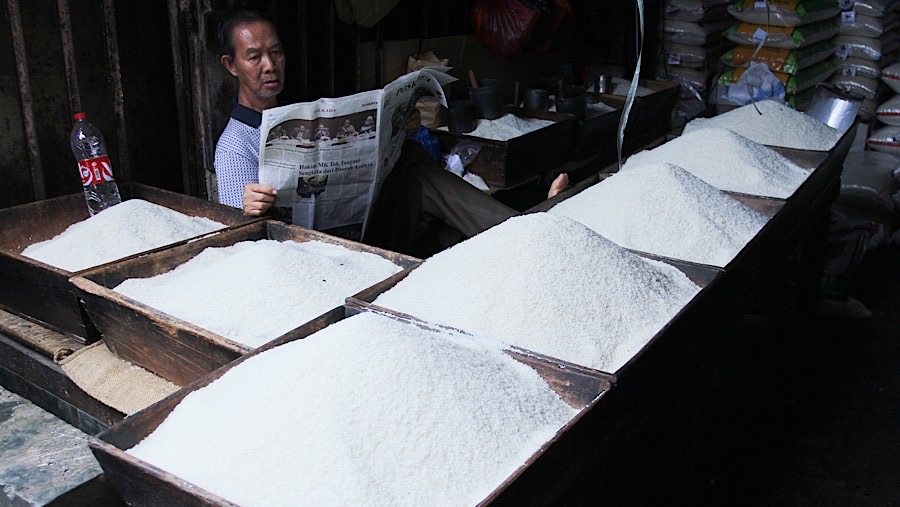 Pedagang beras membaca koran saat menunggu pembeli di Pasar Kebayoran Lama, Jakarta, Selasa (7/12/2025). (Bloomberg Technoz/Andrean Kristianto)
