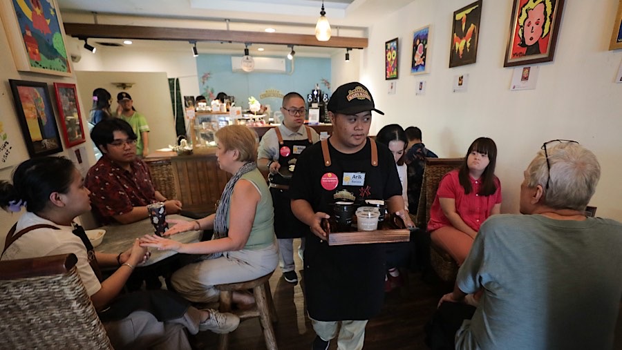 Pekerja penyandang disabilitas down syndrome mengantarkan kopi di Kopi Kamu, Jakarta, Kamis (9/1/2025). (Bloomberg Technoz/Andrean Kristianto)