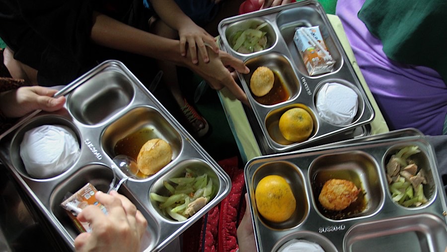 Seorang ibu membuka menu makan bergizi gratis (MBG) di Posyandu Dahlia 2, Ciracas, Jumat (10/1/2025). (Bloomberg Technoz/Andrean Kristianto)