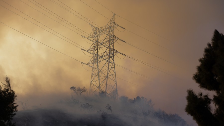 Asap membumbung melewati kabel listrik selama kebakaran Palisades di Los Angeles, California, AS, Sabtu (11/1/2025). (Benjamin Fanjoy/Bloomberg)