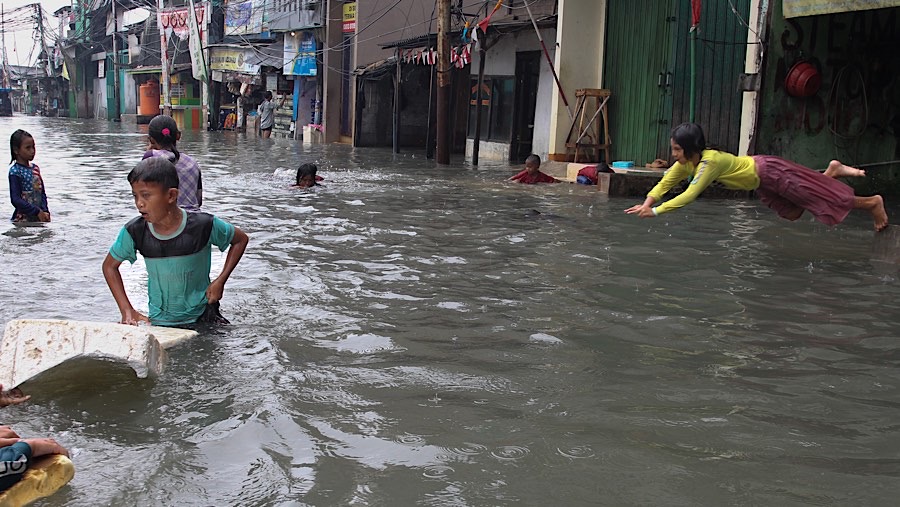 Beberapa anak tampak memanfaatkan banjir untuk bermain air di sekitar lokasi yang terendam. (Bloomberg Technoz/Andrean Kristianto)