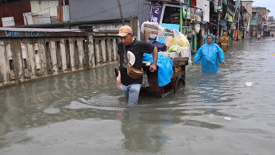 Aktivitas warga di sekitar lokasi pun tetap berjalan seperti biasa meskipun dalam kondisi yang tergenang air. (Bloomberg Technoz/Andrean Kristianto)