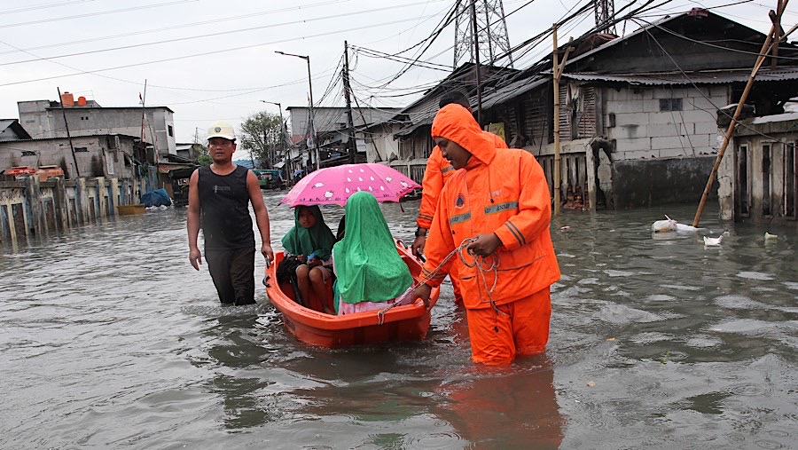 Warga menaiki perahu BPBD saat banjir rob di Muara Angke, Penjaringan, Jakarta Utara, Selasa (14/1/2025). (Bloomberg Technoz/Andrean Kristianto)