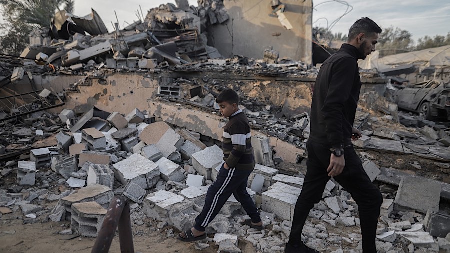 Warga berjalan melewati puing bangunan usai serangan udara Israel di Deir al-Balah, Gaza tengah, Rabu (15/1/2025). (Ahmad Salem/Bloomberg)
