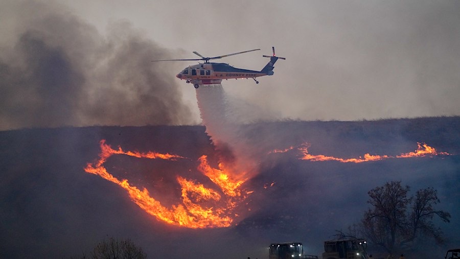 Helikopter menjatuhkan air di lereng bukit selama Kebakaran Hughes di Castaic, California, AS, Rabu, (22/1/2025). (Kyle Grillot/Bloomberg)