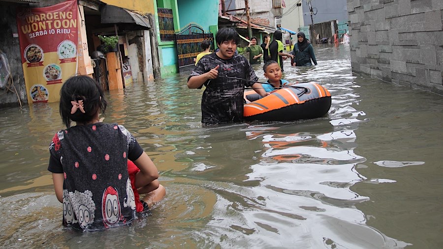 Warga melintasi banjir di kawasan pemukiman Rawa Buaya, Jakarta Barat, Rabu (29/1/2025). (Bloomberg Technoz/Andrean Kristianto)