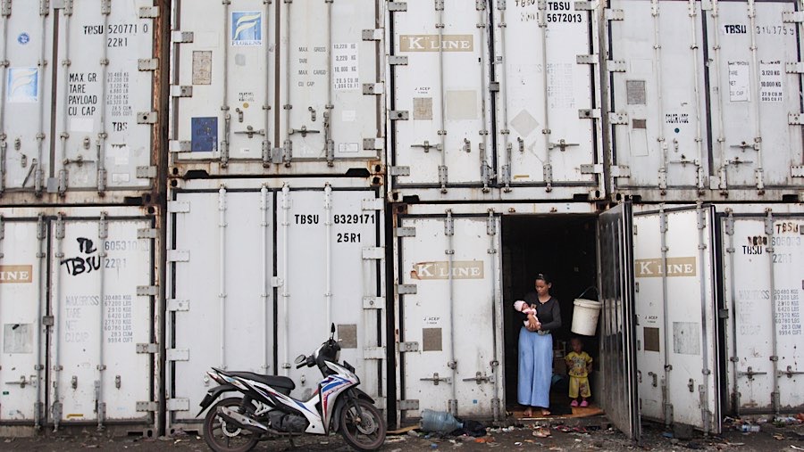 Pengungsi menggendong anaknya di dalam kontainer kosong di Rorotan, Jakarta, Jumat (31/1/2025). (Bloomberg Technoz/Andrean Kristianto)