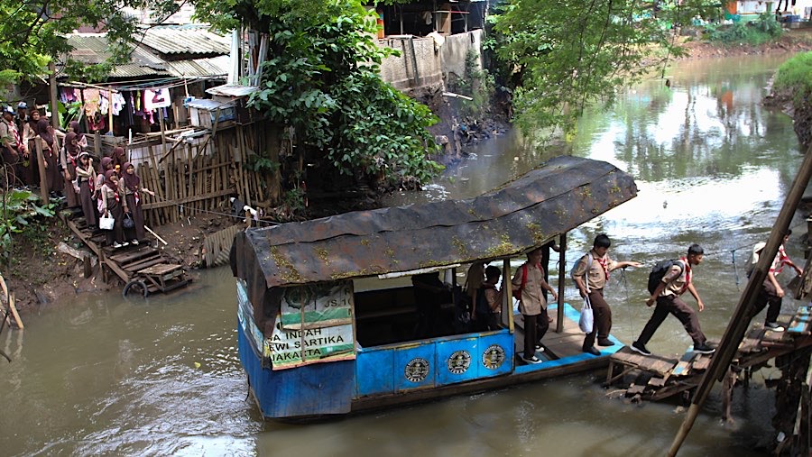 Sejumlah pelajar turun dari perahu eretan di Kali Pesanggrahan, Jakarta, Rabu (5/2/2025). (Bloomberg Technoz/Andrean Kristianto)