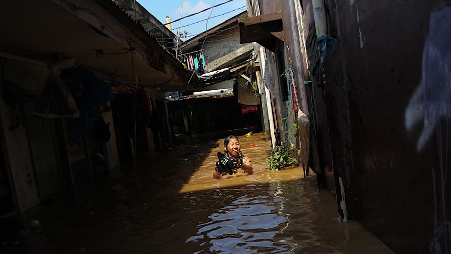 Seorang anak bermain banjir di Jl. Jembatan 1, Balekambang, Jakarta Timur, Senin (3/3/2025). (Bloomberg Technoz/Andrean Kristianto)