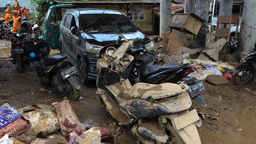 Beberapa kendaraan yang terendam banjir terparkir dengan lumpur yang masih menempel. (Bloomberg Technoz/Andrean Kristianto)